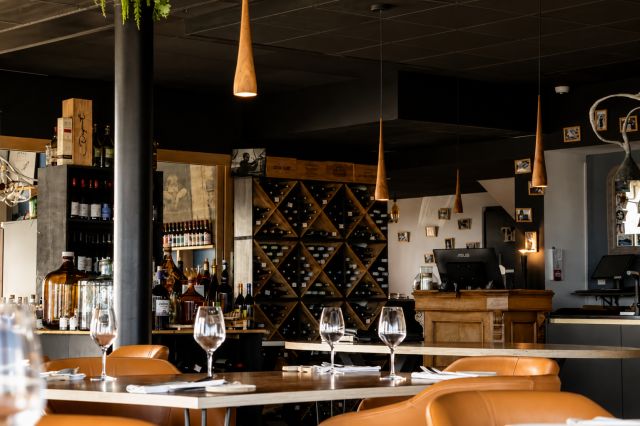 Cave à vin murale et comptoir d'accueil dans la salle du restaurant Le Saltimbanque à Eaucourt-sur-Somme.