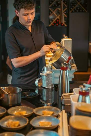 Cuisinier préparant une émulsion crémeuse au passe-plat pour le service, restaurant Le Saltimbanque à Eaucourt-sur-Somme.
